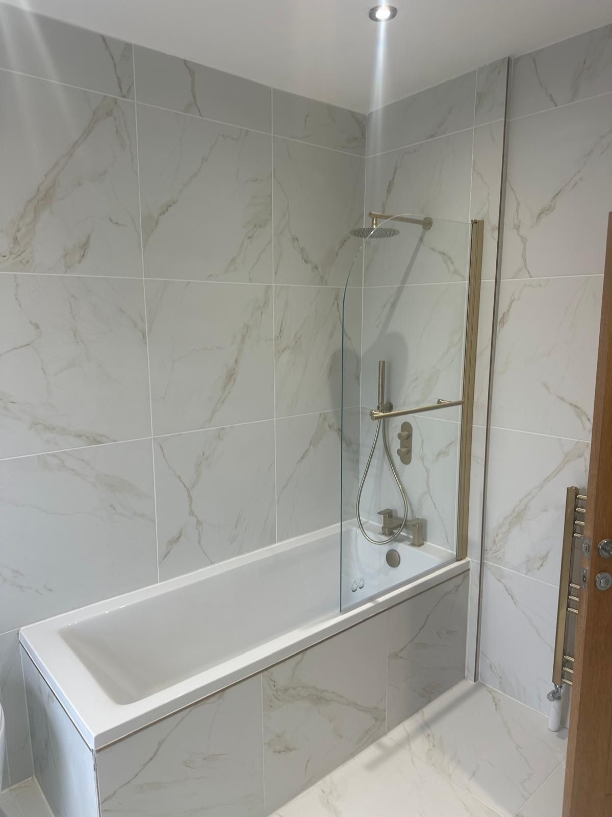 Bath with rainfall shower, glass screen and brushed brass fittings