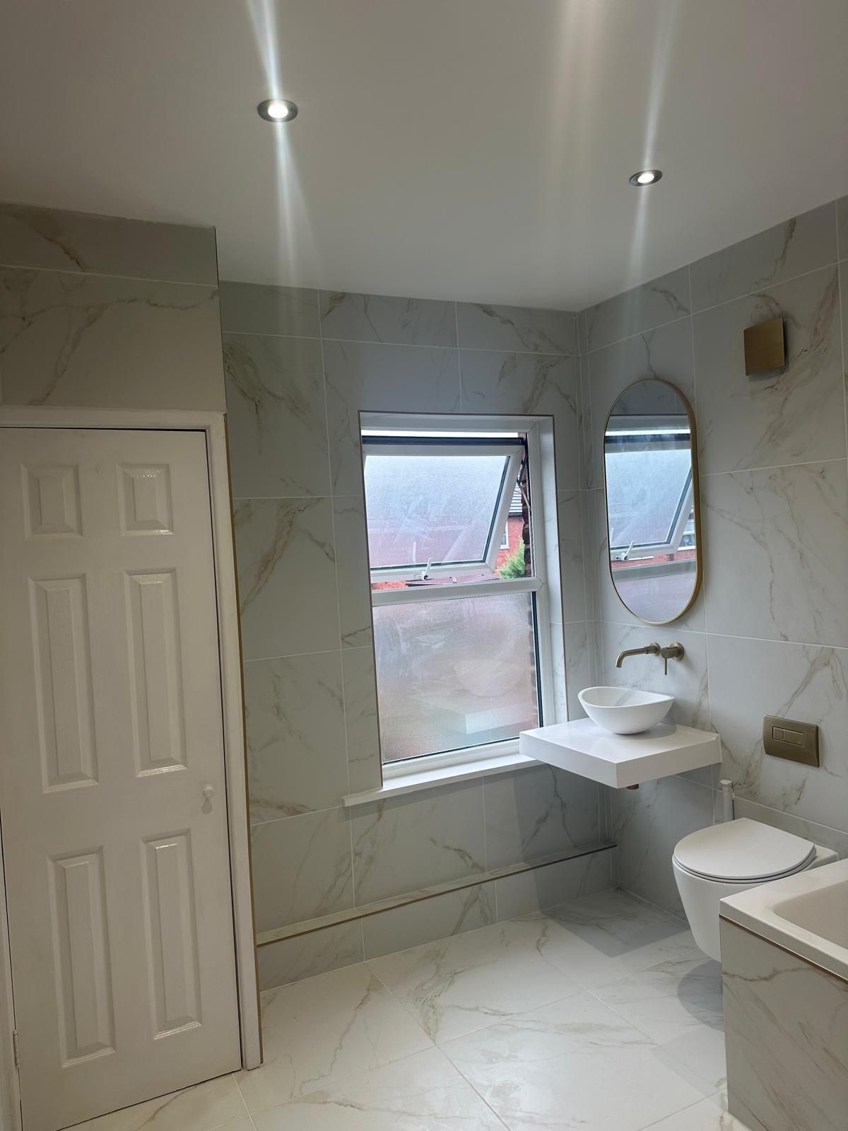 Bathroom with marble-effect porcelain tiles, wall-hung WC, vessel basin and brushed brass taps