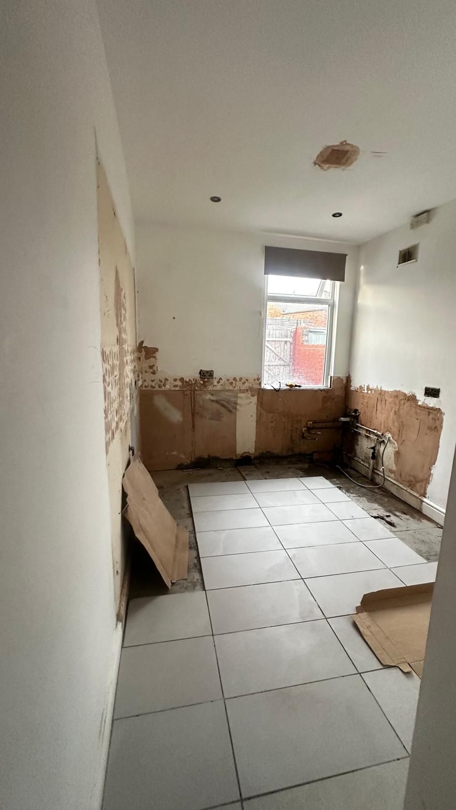 Kitchen stripped back to bare walls with exposed pipework