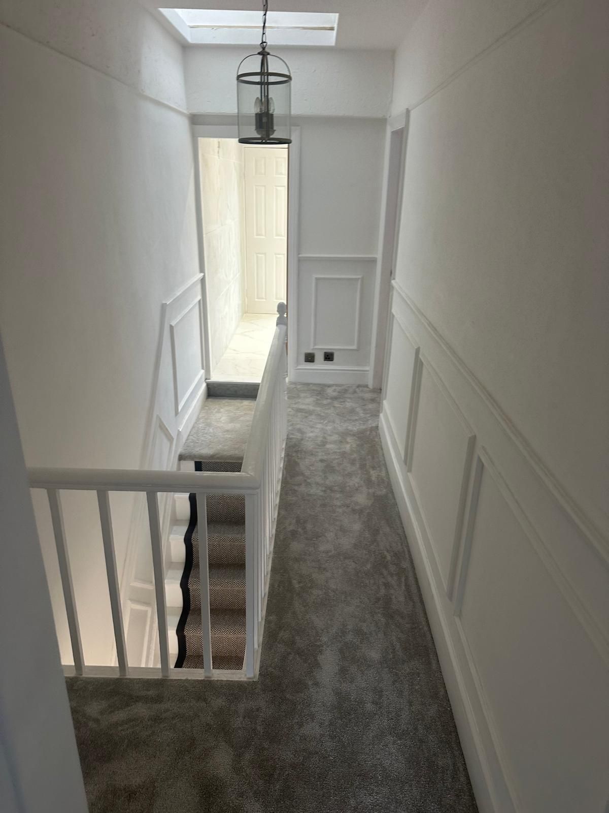 Bright white landing with panelling, lantern light and new grey carpet
