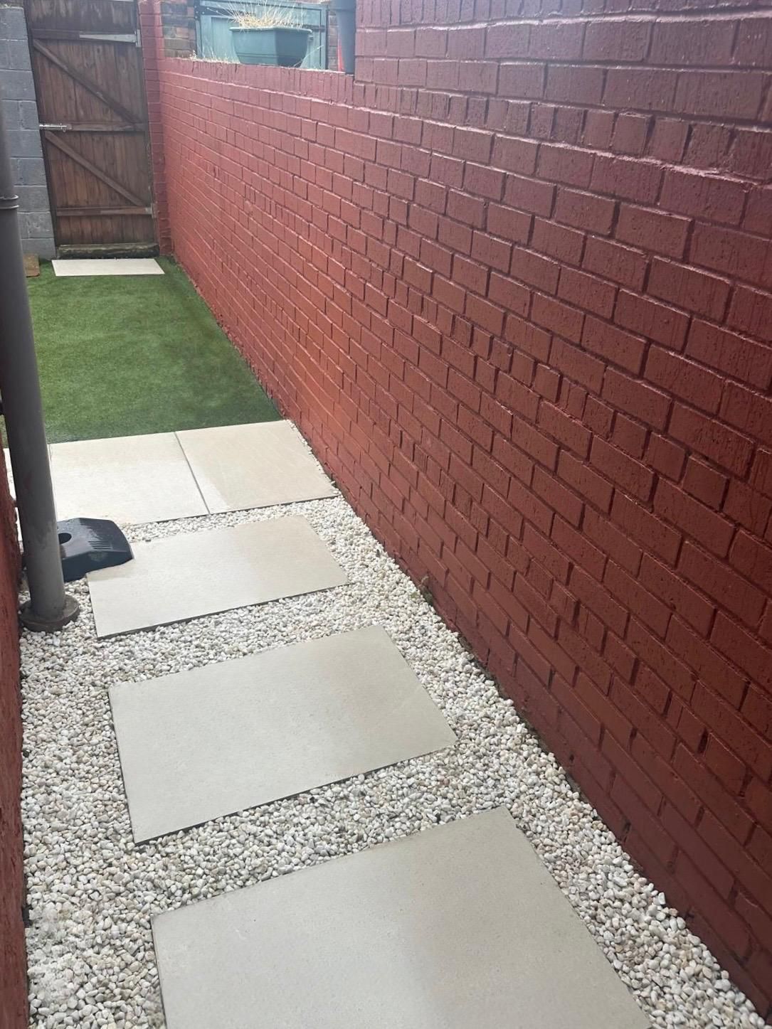 Rear yard with porcelain stepping slabs, white gravel and artificial grass